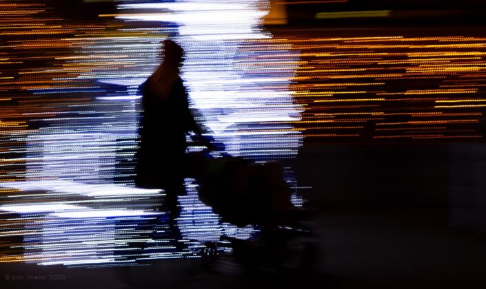 a black silhooet of a mother pushing a stroller against colourful streaks of light composed of discrete square dots; a mosaic of light